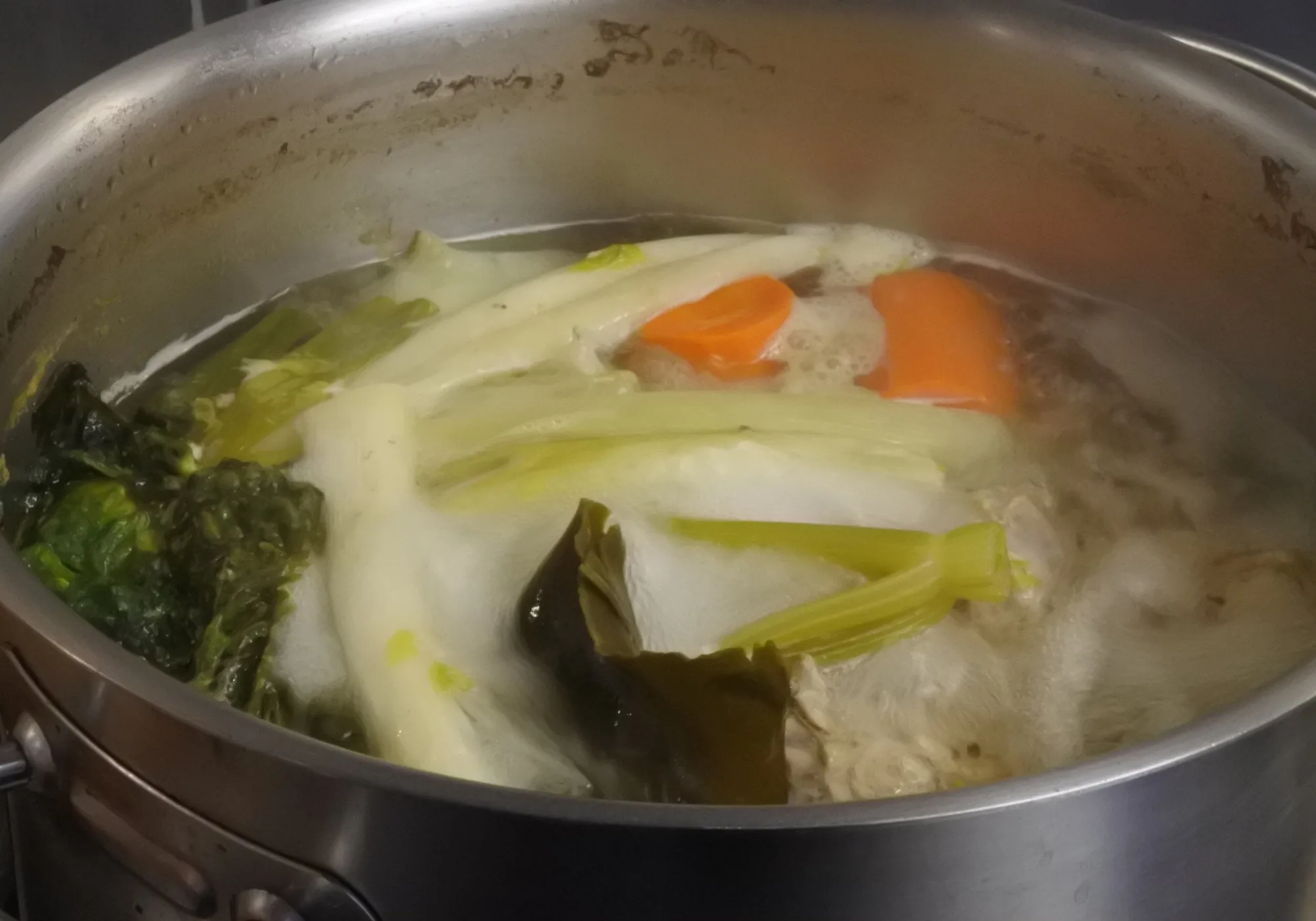 自社キッチンで大鍋にブイヨンを仕込む様子。湯気と野菜