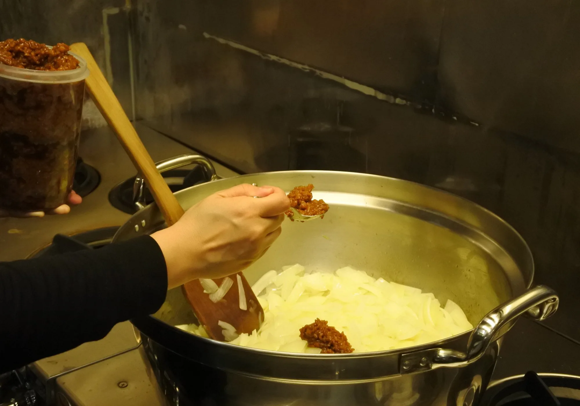 鍋の玉ねぎに麹を加える調理の手元
